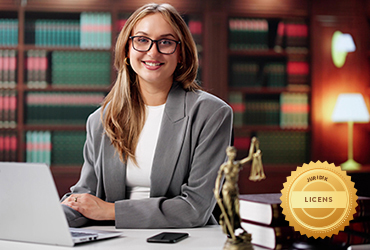 Person vid skrivbord med bokhyllor och fru justitia juridiklicens