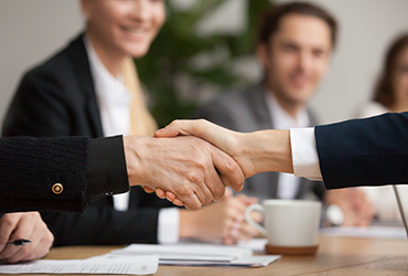 Personer vid ett bord tar i hand över ett avtal