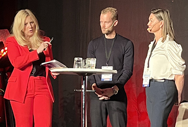 Frida i röd dress, Oscar i svarta kläder och Anna i ljus topp samtalar på MOA